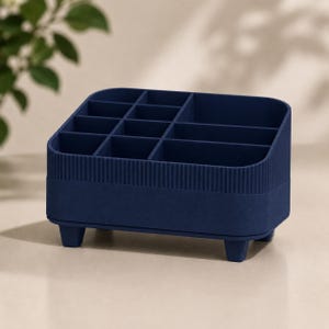 May include: A dark blue desk organizer featuring multiple compartments of varying sizes for storage. The exterior has a ribbed texture on the upper section and a smooth finish on the lower base, supported by four small, sturdy feet at the corners.
