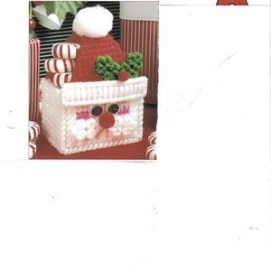 May include: A white crochet Santa Claus mini basket with a red hat, green holly, and candy canes. The basket is a Christmas craft project.