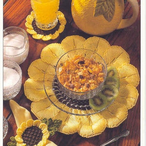 May include: A sunflower breakfast set with a yellow pitcher, coasters, and placemats. The set includes a glass of orange juice, a bowl of cereal, and a napkin ring. The text "SUNFLOWER BREAKFAST SET" is at the top.