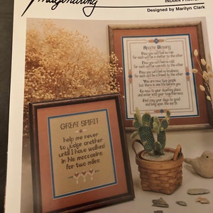 May include: Two framed cross-stitch patterns with Native American themes. The top pattern is titled "Apache Blessing" and includes the text "Now you will feel no rain for each will be a shelter to the other." The bottom pattern is titled "Great Spirit" and includes the text "Help me never to judge another until I have walked in his moccasins for two miles."