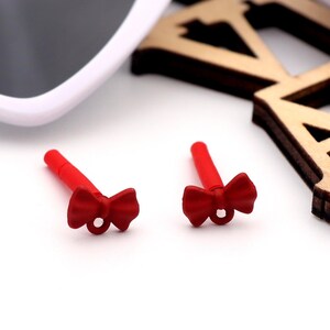 May include: Two red bow-shaped silicone earplugs for swimming or other water activities.