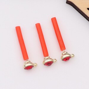 May include: Three orange and gold decorative sticks with red rhinestone accents.