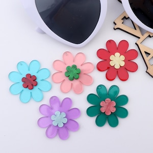 May include: Five colorful acrylic flower charms with a smaller flower in the center. The flowers are in shades of pink, red, blue, green, and purple.
