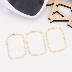 May include: Three gold-colored metal rectangular frames with a textured surface. The frames have a small loop at the top.