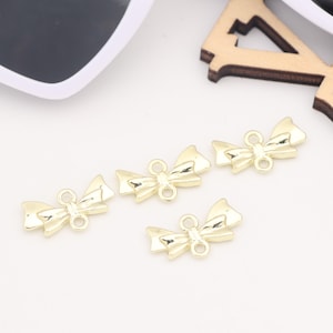 以下が含まれることがあります： 裏側に2つのループが付いた、金色の金属製の弓形のチャームが4つ。チャームは、ジュエリー作りやその他のクラフトプロジェクトに使用するために設計されています。