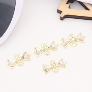 May include: Four gold-toned metal connectors with clear crystal triangle accents. Each connector has two loops for attaching jewelry.