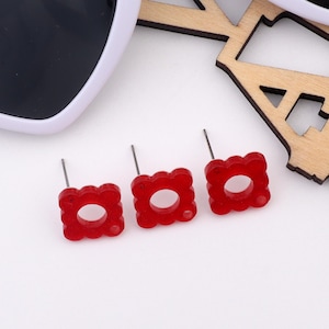 Pode incluir: Três pares de brincos quadrados vermelhos com um círculo recortado no centro. Os brincos têm um  pino prateado.