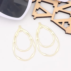 May include: Two gold-toned metal earring blanks in a teardrop shape with a double-layered design. The blanks have a smooth, slightly textured finish.