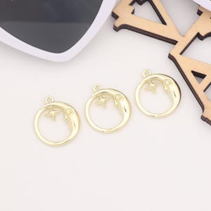 May include: Three gold-tone metal charms shaped like a crescent moon with a star inside. Each charm has a small loop at the top for attaching to a necklace or bracelet.