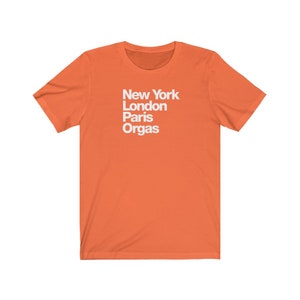 Puede incluir: Camiseta naranja de manga corta con texto blanco que dice "New York London Paris Orgas".