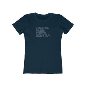 May include: A navy blue t-shirt with the text "LONDON PARIS TOKYO BED-STUY" printed in white.