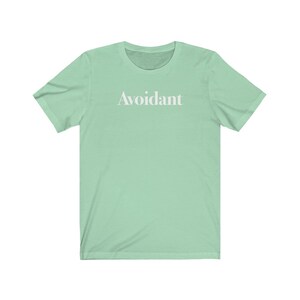 May include: A light green t-shirt with the word "Avoidant" printed in white on the front.