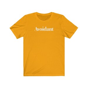 May include: A yellow short-sleeved t-shirt with the word "Avoidant" printed in white on the front.