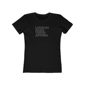 May include: Black women's t-shirt with white text that reads "LONDON PARIS TOKYO ASTORIA"