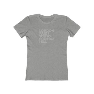 May include: Gray short-sleeved t-shirt with the words "LONDON PARIS TOKYO CLINTON HILL" printed in white.