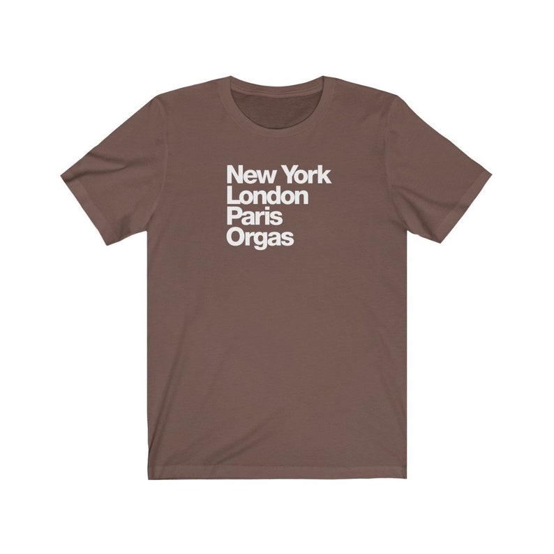 Puede incluir: Una camiseta marr&oacute;n con texto blanco que dice "New York London Paris Orgas"