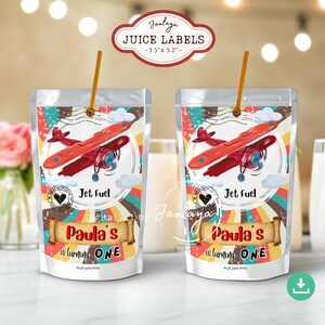 May include: Two juice boxes with airplane graphics. Each box has a red airplane design, the text "Jet Fuel", and "Paula's is turning ONE". The label at the top says "JUICE LABELS -3.5" x 5.2"" with the name "Janlaya".