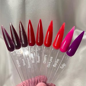 Może przedstawiać: Kolekcja próbek paznokci akrylowych w różnych odcieniach czerwieni, różu i fioletu. Każda próbka jest oznaczona nazwą koloru, w tym "Orchid", "Velvet", "Wine", "Rose", "Cherry", "Dark pink", "Barbie" i "Tulip".