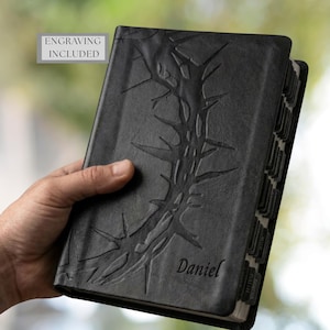 May include: Black leather-bound book with embossed thorn design and the name "Daniel" in script. The book has labeled page dividers and the text "ENGRAVING INCLUDED" in a gray box.
