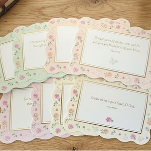 May include: A collection of pastel-colored cards with scalloped edges and floral designs. Each card features a gold-bordered frame with text, including phrases like "Delight yourself in the Lord" and "Create in me a pure heart, O God."
