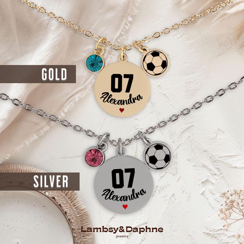 K&ouml;nnte beinhalten: Zwei Halsketten mit einem Fu&szlig;ball-Anh&auml;nger, einem Kristall-Anh&auml;nger und einem runden Anh&auml;nger mit der Nummer 07 und dem Namen Alexandra. Die obere Halskette ist golden und die untere Halskette ist silber.