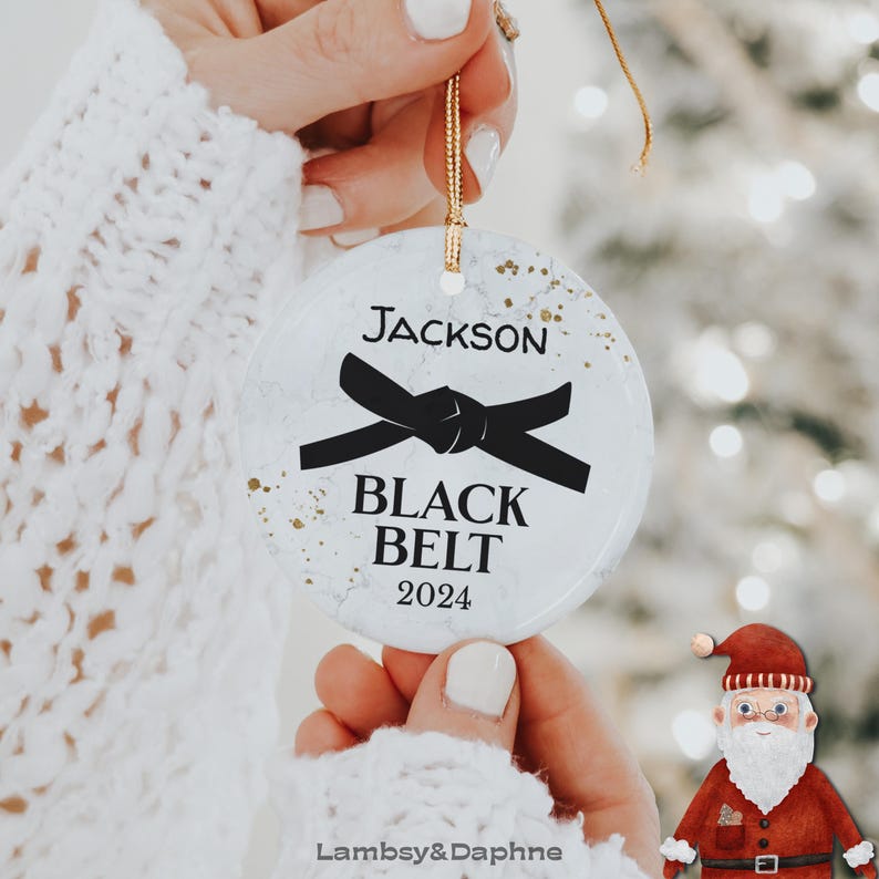 May include: White round Christmas ornament with a black belt design and the text "Jackson Black Belt 2024".