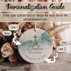May include: A white ceramic ornament with a watercolor-style design in shades of blue and gold. The ornament features a gold cross, the name "Joshua Matthews", and the text "Baptized Oct 28, 2024".