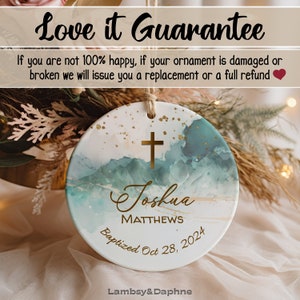 May include: A white ceramic ornament with a blue and gold watercolor design. The ornament features a gold cross, the name "Joshua Matthews", and the text "Baptized Oct 28, 2024".