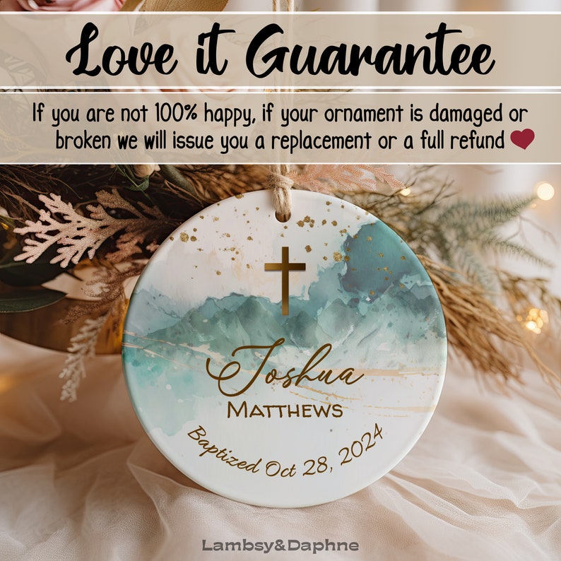 May include: A white ceramic ornament with a blue and gold watercolor design. The ornament features a gold cross, the name "Joshua Matthews", and the text "Baptized Oct 28, 2024".