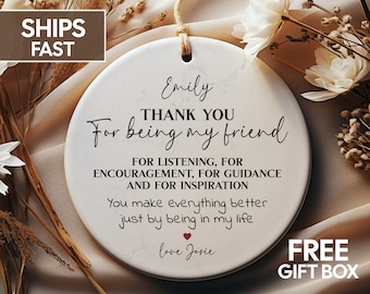 May include: A white round ceramic ornament with a marbled effect. The ornament features black text that reads "Emily THANK YOU For being my friend FOR LISTENING, FOR ENCOURAGEMENT, FOR GUIDANCE AND FOR INSPIRATION You make everything better just by being in my life love Josie". There is a small red heart symbol between the text "life" and "love".