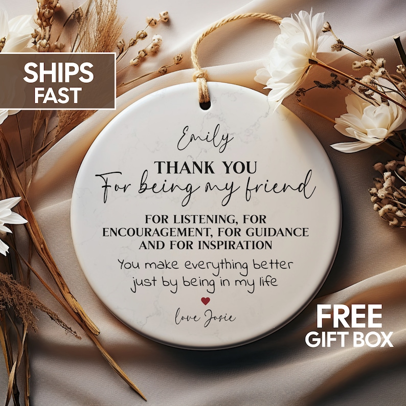 May include: White ceramic round ornament with a marbleized pattern. The ornament has black text that reads "Emily THANK YOU For being my friend FOR LISTENING, FOR ENCOURAGEMENT, FOR GUIDANCE AND FOR INSPIRATION You make everything better just by being in my life love Josie". There is a small red heart symbol between the text "life" and "love".