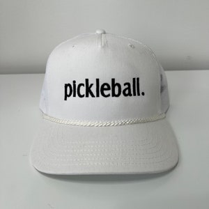 May include: White mesh trucker hat with a white rope trim and black embroidered text that says "pickleball."