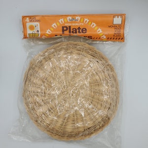 May include: A package of four woven wicker plate holders. The package is orange and white with the text "High Quality Plate Holders" and "Woven to hold your paper plates".
