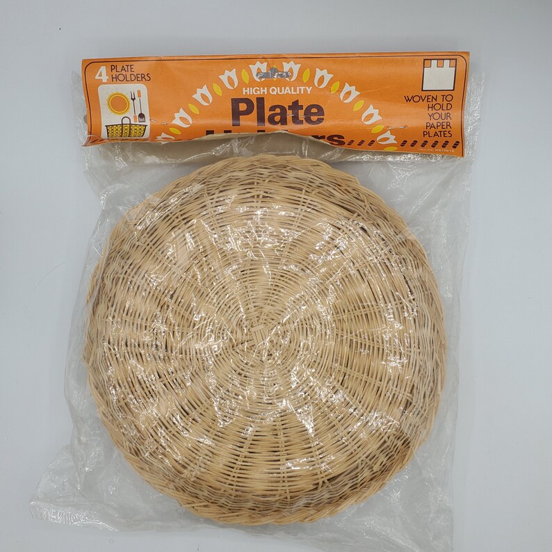 May include: A package of four woven wicker plate holders. The package is orange and white with the text "High Quality Plate Holders" and "Woven to hold your paper plates".