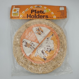 Peut inclure: Un paquet de quatre supports à assiettes en osier tissé. L'emballage est orange et blanc avec le texte "High Quality Plate Holders" et "Woven to Hold Your Paper Plates". Les supports sont illustrés sur l'emballage en cours d'utilisation pour des fêtes, des collations et des pique-niques.