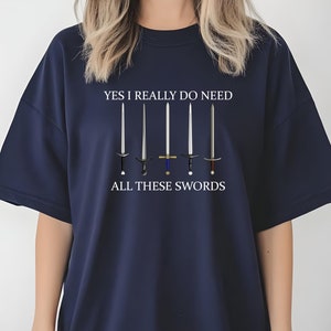 May include: A navy blue t-shirt with the text "YES I REALLY DO NEED ALL THESE SWORDS" and a graphic of six swords.