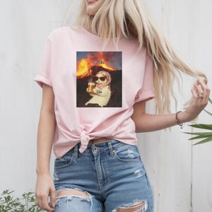 May include: Pink t-shirt with a graphic of a cat wearing sunglasses and holding a beer in front of a volcano. The text "My Life" is above the cat and the text "Me" is below the cat.