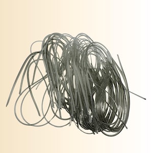 May include: A tangled bundle of clear, flexible tubing. The tubing is a translucent gray color and appears to be made of plastic or a similar material. The tubes are curved and looped, creating a dense, intertwined mass.