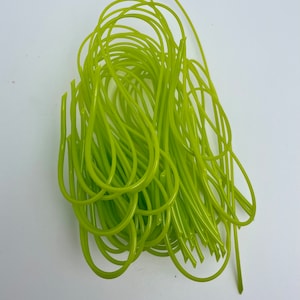 May include: A pile of bright green, flexible, plastic tubing. The tubing is smooth and shiny, with a slightly translucent appearance. The loops and curves of the tubing create a tangled, yet organized, arrangement. The background is plain white.