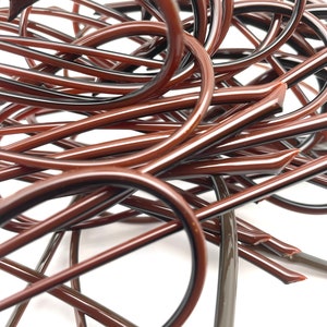 May include: A close-up shot of a tangled collection of brown, curved, and straight plastic pieces. The pieces have a glossy finish and are arranged against a white background. The shapes vary, with some forming loops.