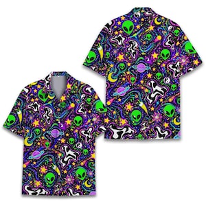 Könnte beinhalten: Zwei kurzärmelige Hemden mit einem lebendigen, psychedelischen Alien-Muster. Das Design zeigt grüne Alien-Gesichter, Planeten, Sterne und wirbelnde kosmische Elemente auf einem schwarzen Hintergrund mit lila, blauen und gelben Akzenten.