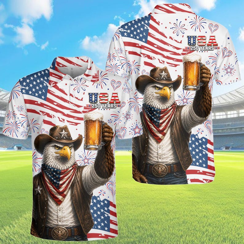 Peut inclure: Polo blanc avec un motif patriotique repr&eacute;sentant le drapeau am&eacute;ricain, des feux d'artifice et un aigle portant un chapeau de cowboy, tenant une bi&egrave;re. Le t-shirt porte l'inscription "USA 250 YEARS".