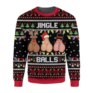 Op de afbeelding: Een zwart sweatshirt met lange mouwen en ronde hals met een feestelijk patroon met rode en witte accenten. Het ontwerp bevat de tekst JINGLE BALLS en drie geïllustreerde figuren met een rendierneus, kerstmuts en hoge hoed.