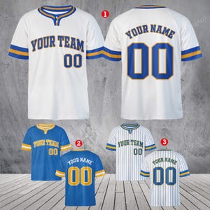 Può includere: Maglia da baseball bianca con dettagli blu e oro. Il davanti mostra "YOUR TEAM" e il numero "00". Il retro mostra "YOUR NAME" e il numero "00". Sono mostrate anche maglie aggiuntive in blu e bianco.
