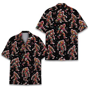 May include: A short-sleeved button-down shirt with a black background featuring an all-over repeating pattern of Bigfoot figures composed of colorful flowers and small butterflies scattered throughout the design in various vibrant shades.