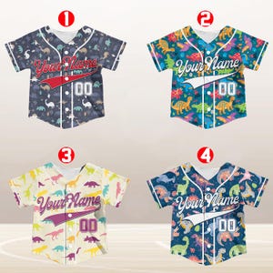 May include: Four baseball jerseys with dinosaur patterns. The jerseys are in different colors, including blue, green, yellow, and purple. Each jersey has the text "Your Name" and the number "00" printed on it.
