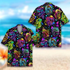Puede incluir: Una camisa de manga corta con botones sobre un fondo negro que presenta un patrón vibrante de colores neón con varios dinosaurios, formas geométricas, triángulos y círculos. El diseño incluye acentos brillantes en rosa, verde, azul y amarillo.