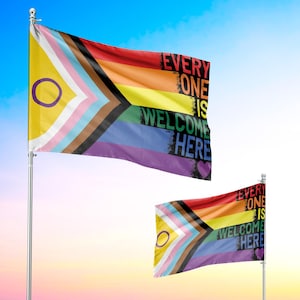 May include: Two flags with a rainbow design and the text "EVERYONE IS WELCOME HERE". The flags feature the Progress Pride flag and the Intersex-Inclusive Pride flag. The flags are waving against a blue sky.