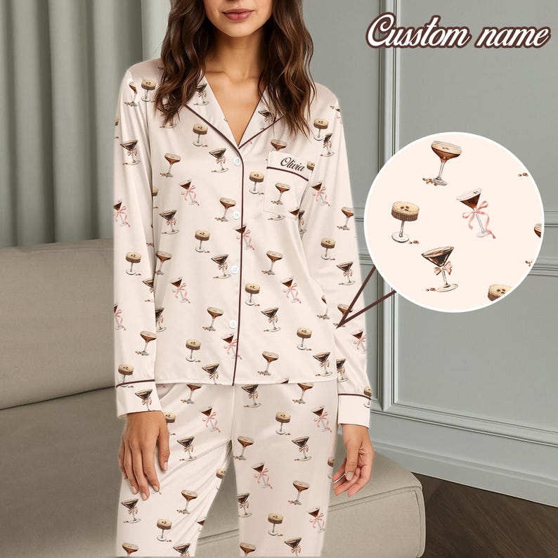 May include: Cream-coloured pyjama set featuring a pattern of martini glasses and pink bows. The long-sleeved top and trousers have dark brown trim. The top has a breast pocket with the name "Olivia" embroidered. The words "Custom name" are at the top.