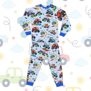 May include: Light blue pajama set featuring a repeating pattern of colorful monster trucks. The long-sleeved top and pants have blue trim and a crew neck. The trucks are in various colors, including green, orange, and purple.